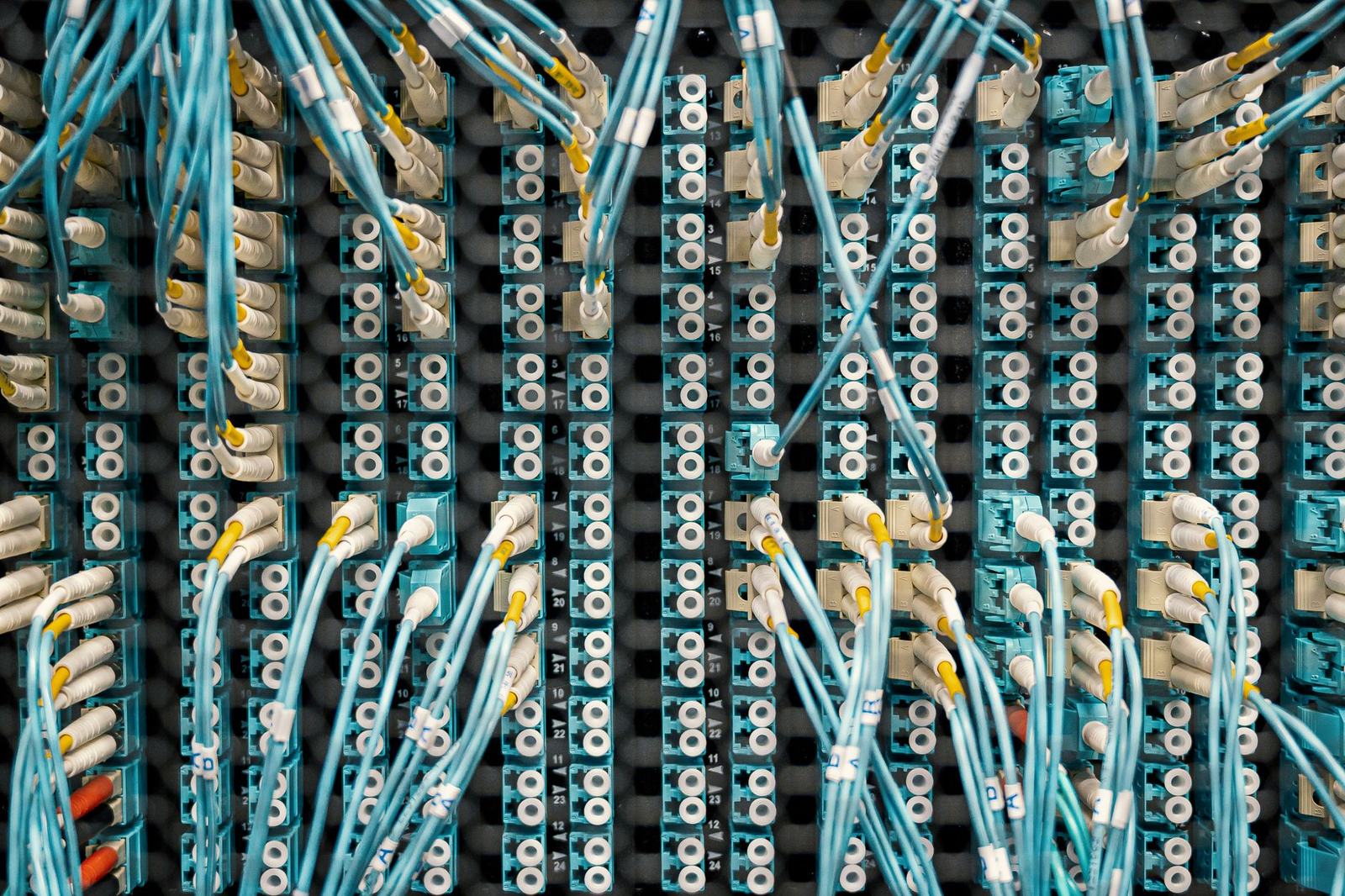 Panel de fibra óptica visto desde arriba, con decenas de cables enlazando puertos de redes distintas