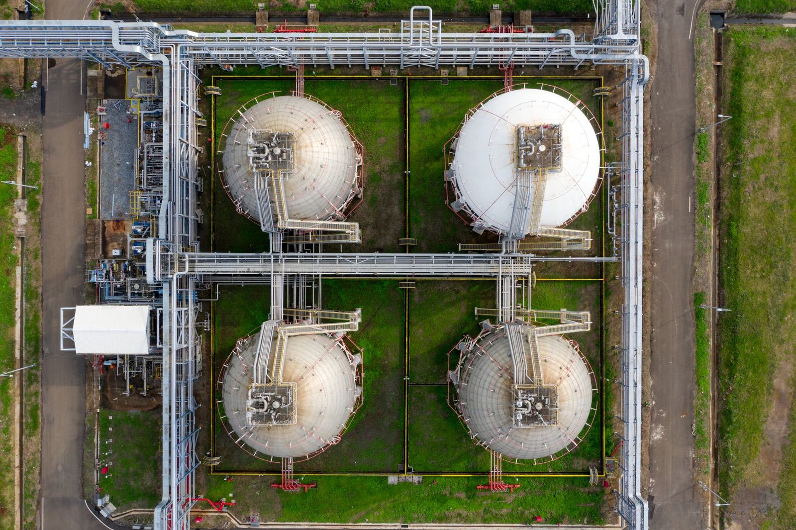 Vista aérea de una planta industrial de gas con cuatro tanques esféricos y una red de tuberías