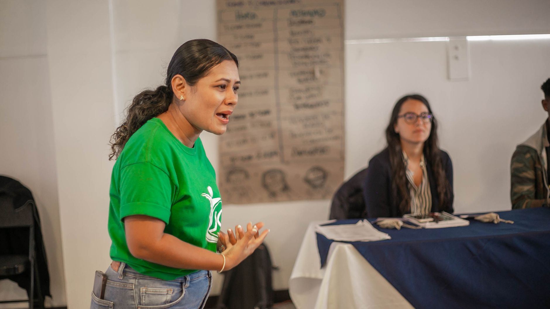 Una mujer explica de pie frente al grupo en una sesión informativa de una organización comunitaria