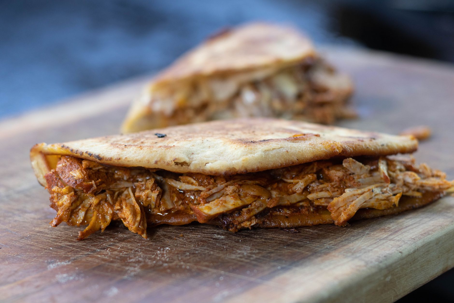Arepa abierta por la mitad y rellena hasta el borde sobre una tabla de madera