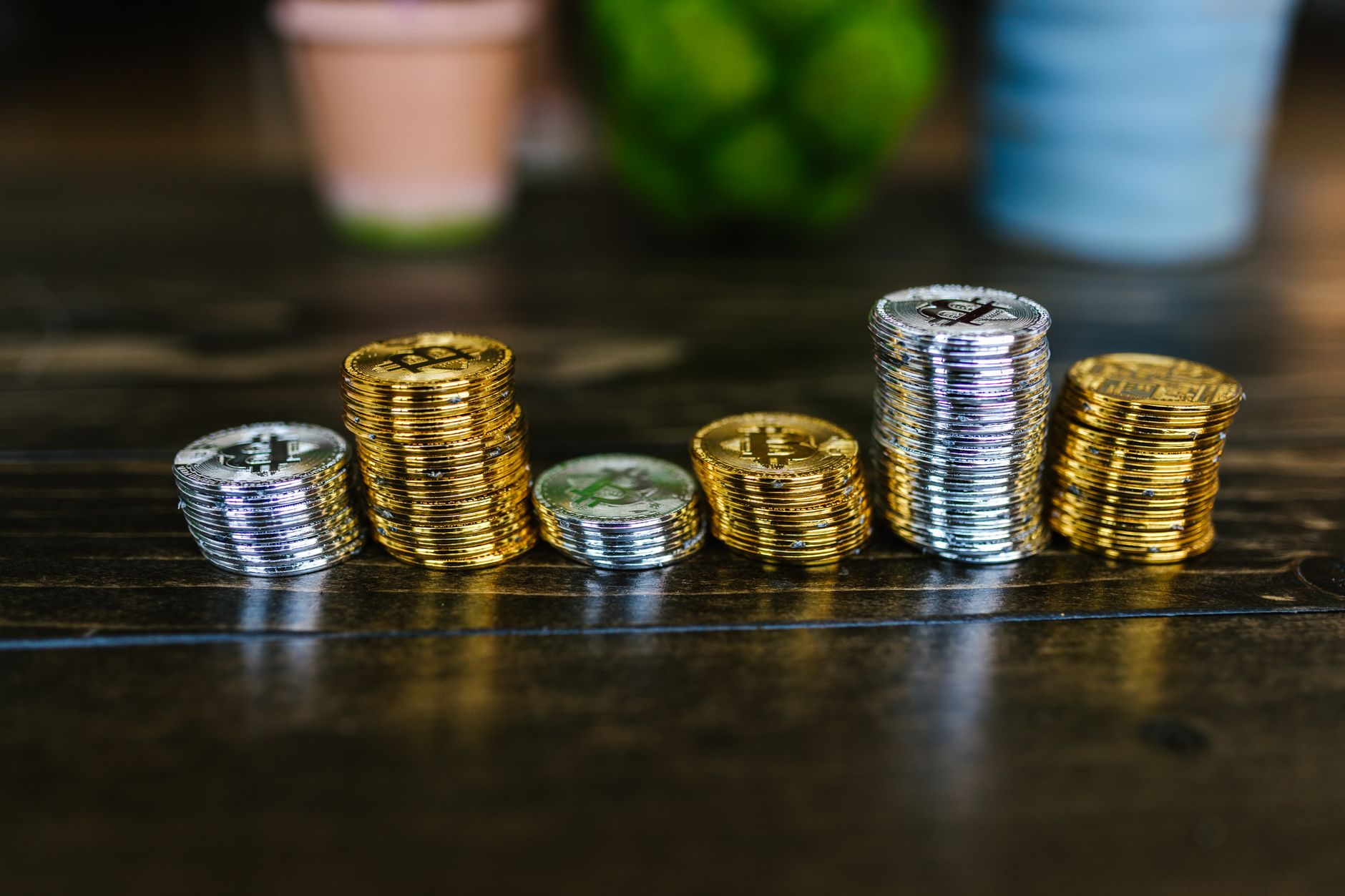 Seis pilas de monedas de criptomoneda de distinta altura sobre una mesa de madera oscura