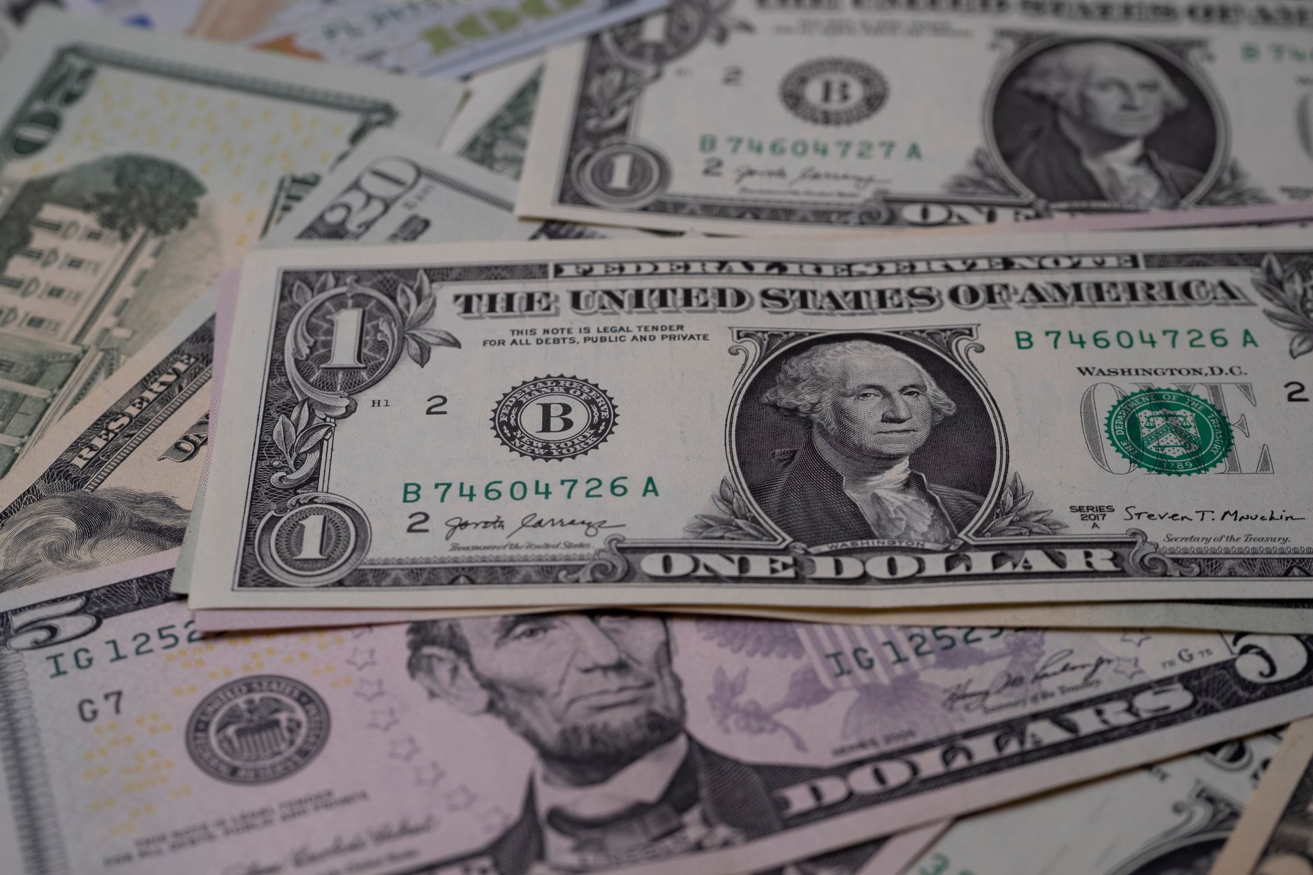Billetes de dólar estadounidense de uno, cinco y veinte dólares esparcidos sobre una mesa