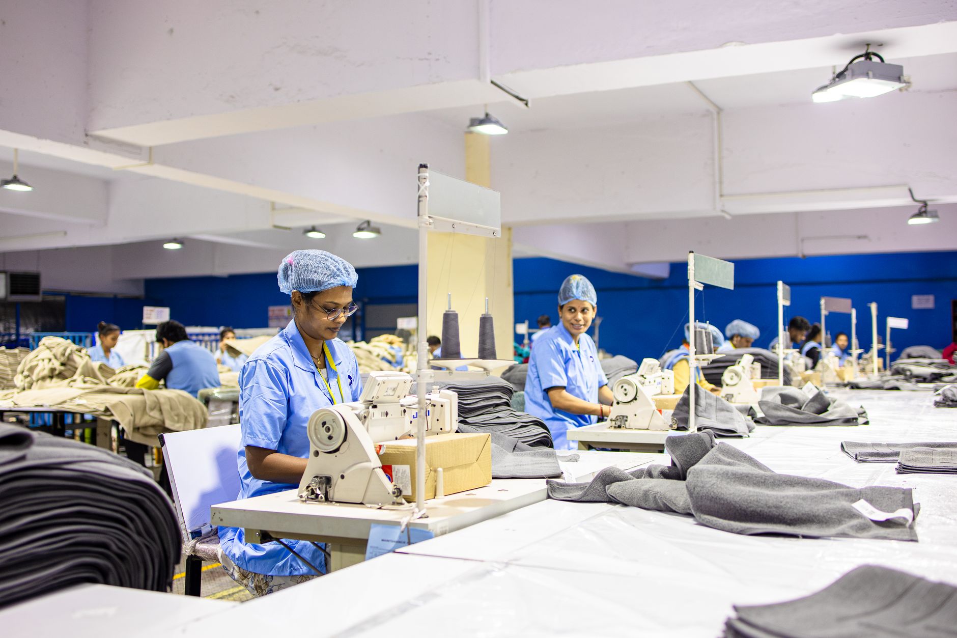 Operarias cosen prendas en fila en el taller de una fábrica textil