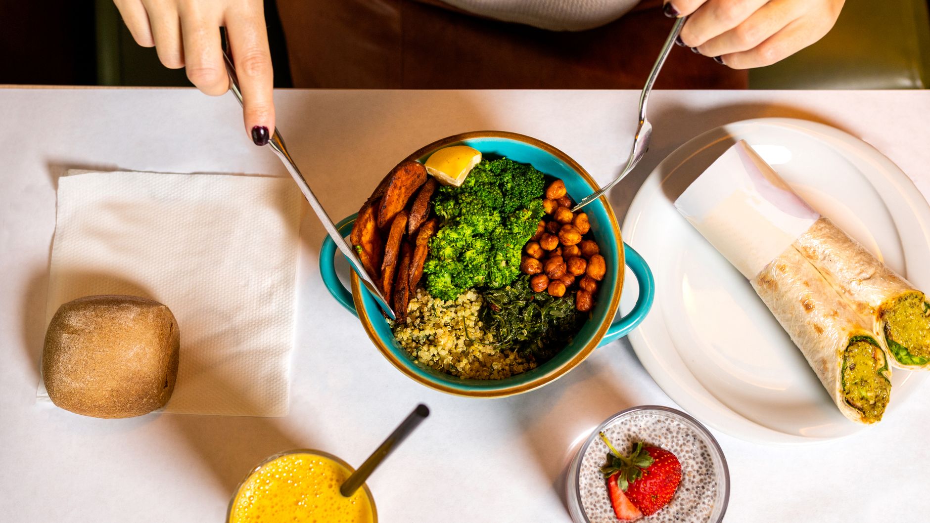 Bowl de quinoa con garbanzos asados, brócoli y kale que alguien empieza a comer en la mesa