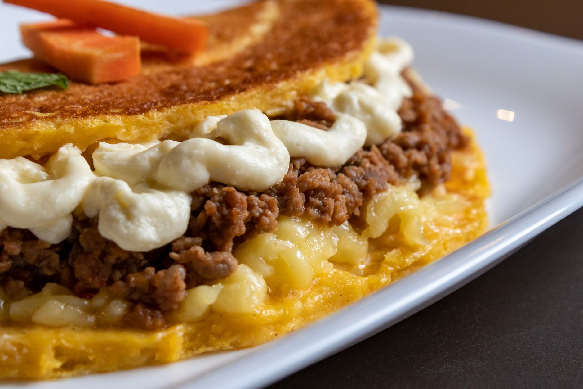 Cachapa doblada por la mitad con el queso derretido asomando entre la masa