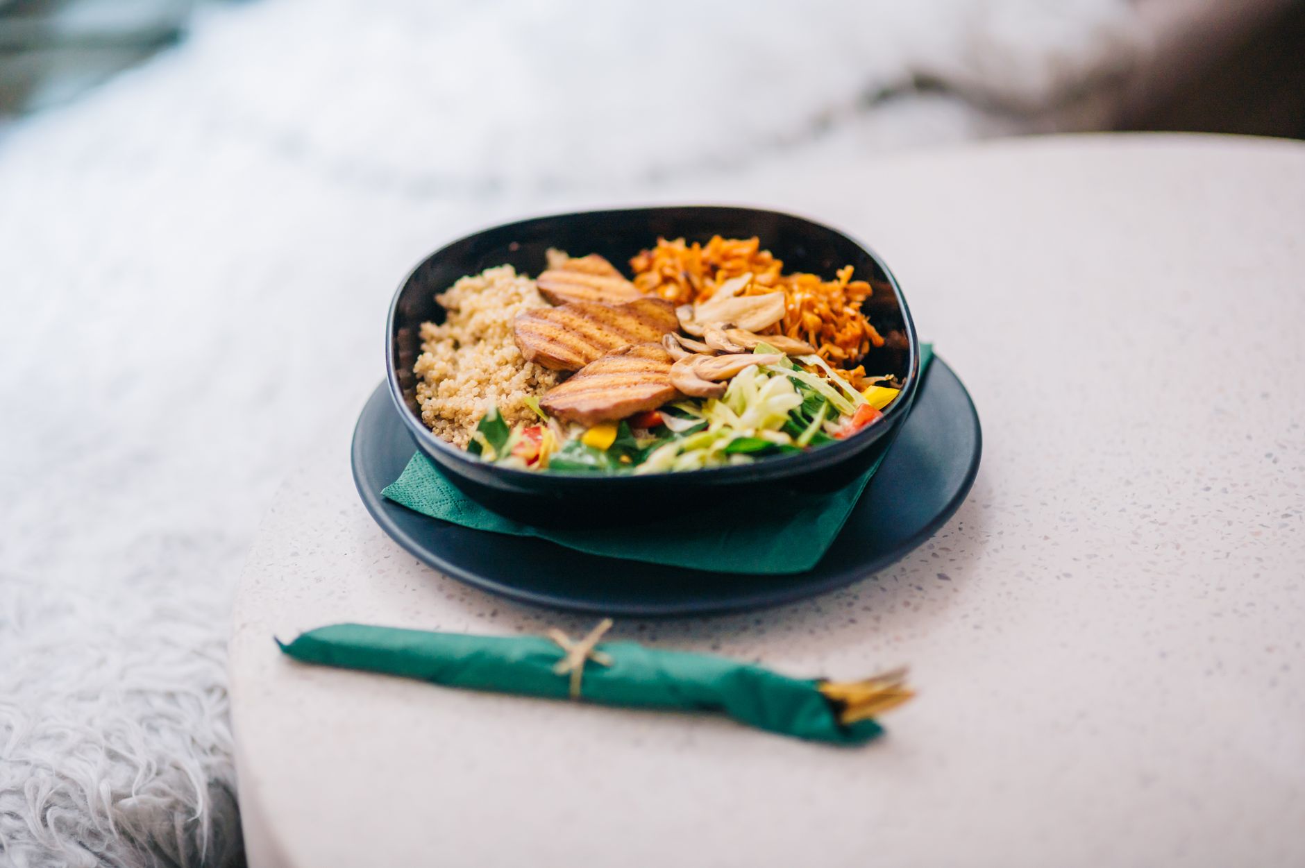 Bowl servido con quinoa, pollo a la plancha, zanahoria rallada, champinones y hojas verdes