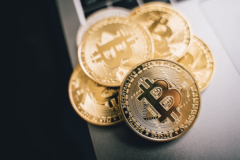 Monedas físicas de Bitcoin doradas apiladas sobre la superficie gris de un portátil