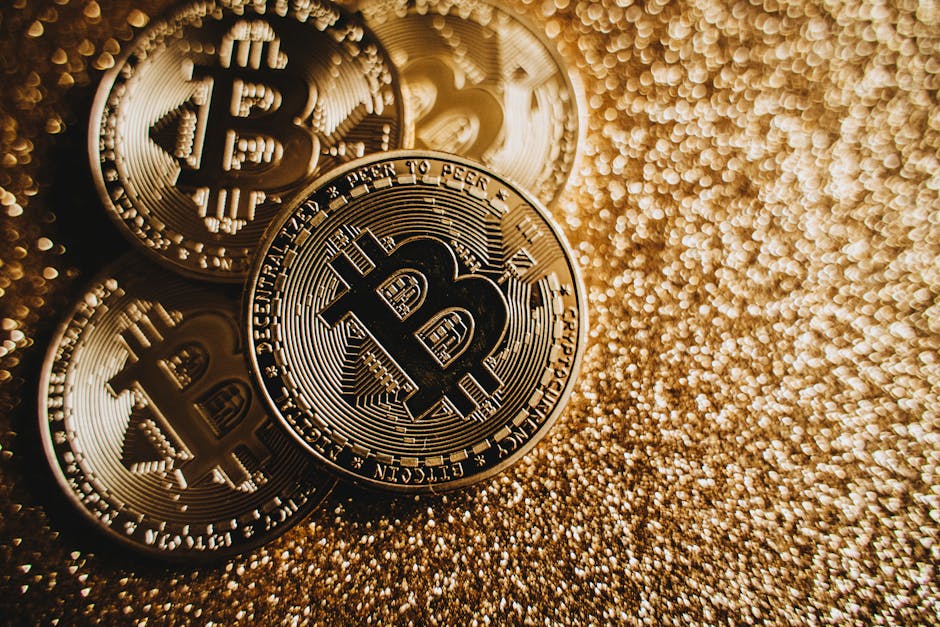 Tres monedas doradas de Bitcoin apiladas sobre una superficie brillante con destellos dorados