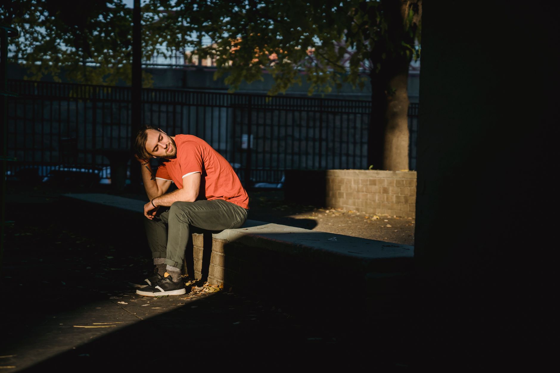 Hombre joven sentado solo en un banco de un parque urbano, pensando en los pasos que siguen
