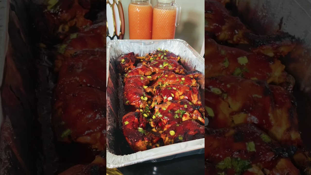 Costillas de cerdo asadas con salsa barbacoa y cebollino picado, servidas en una bandeja de aluminio rectangular