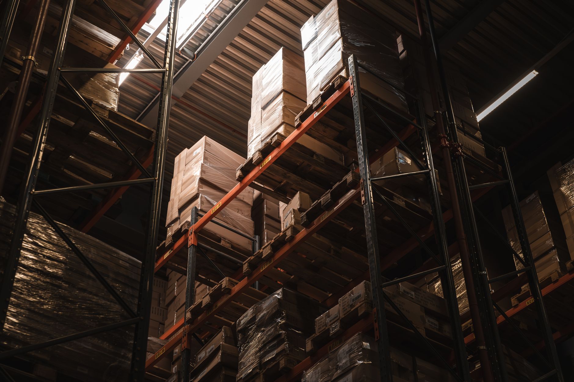 Palés de cajas de cartón precintadas apiladas en las estanterías altas de un almacén de distribución