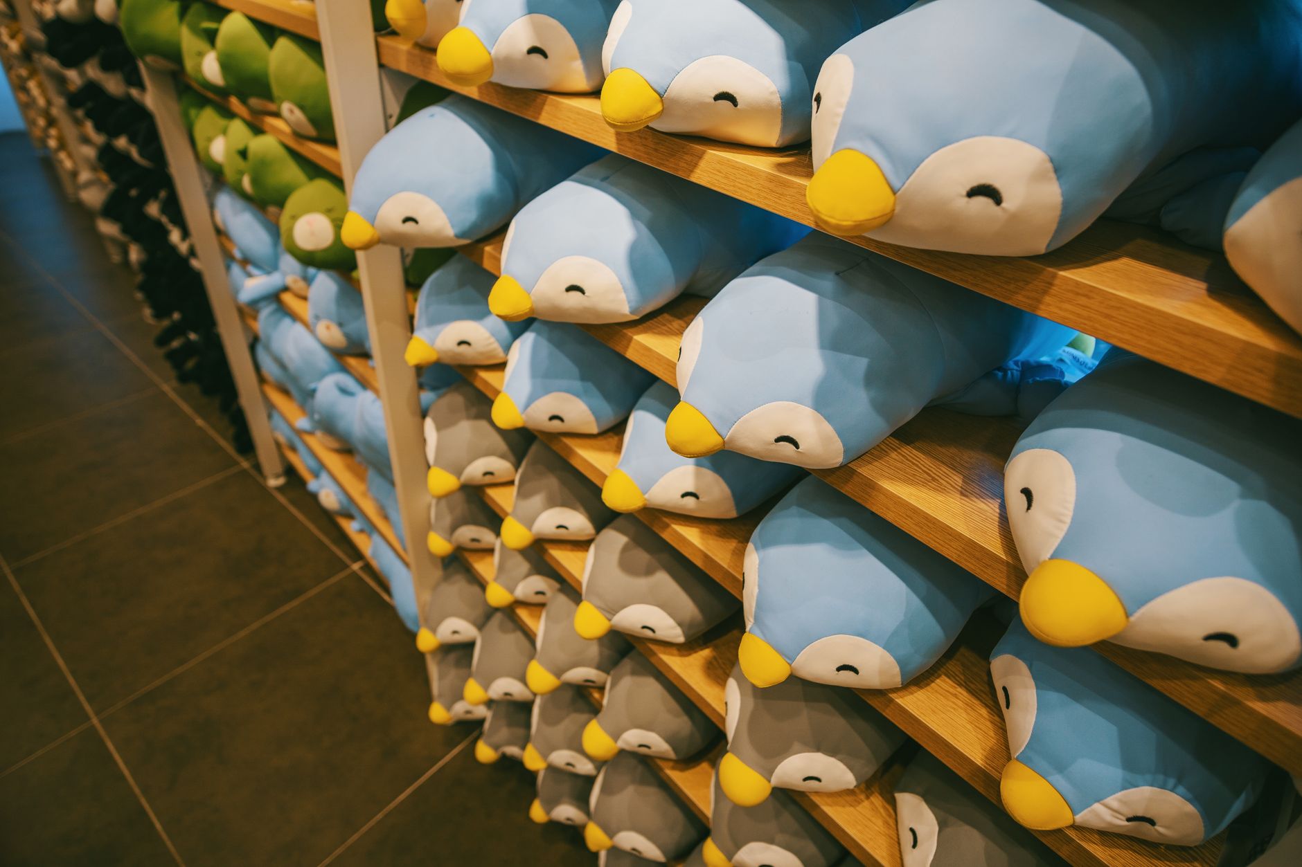Filas de pingüinos de peluche azules ordenados en las estanterías de madera de una tienda