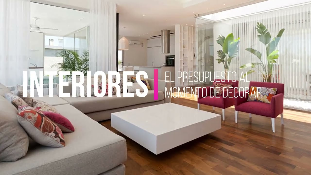 Amplia sala con sofá gris, mesa baja blanca, dos sillones fucsias, plantas y texto superpuesto en blanco.
