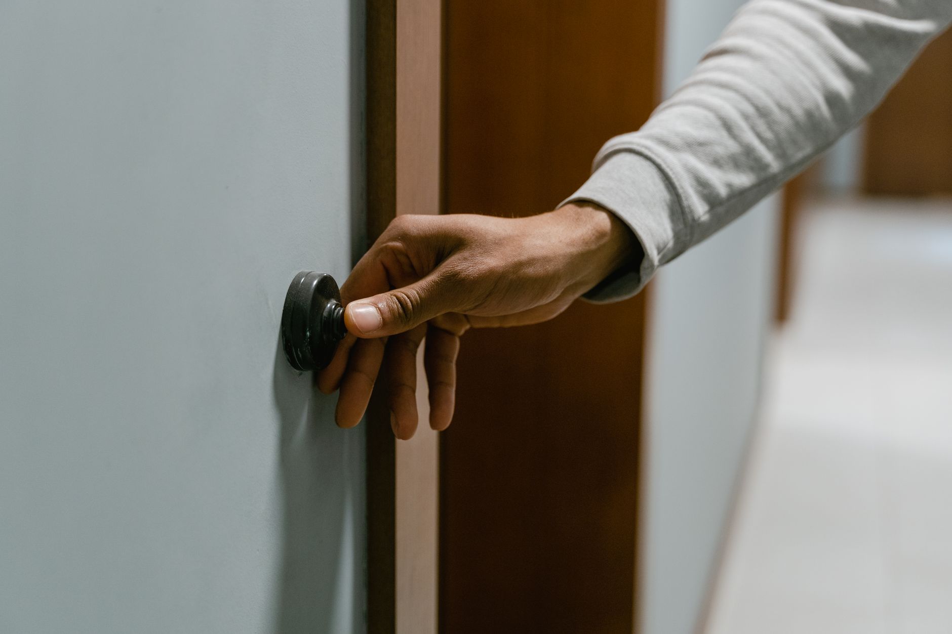 Una mano pulsa el timbre junto a la puerta de entrada de una vivienda