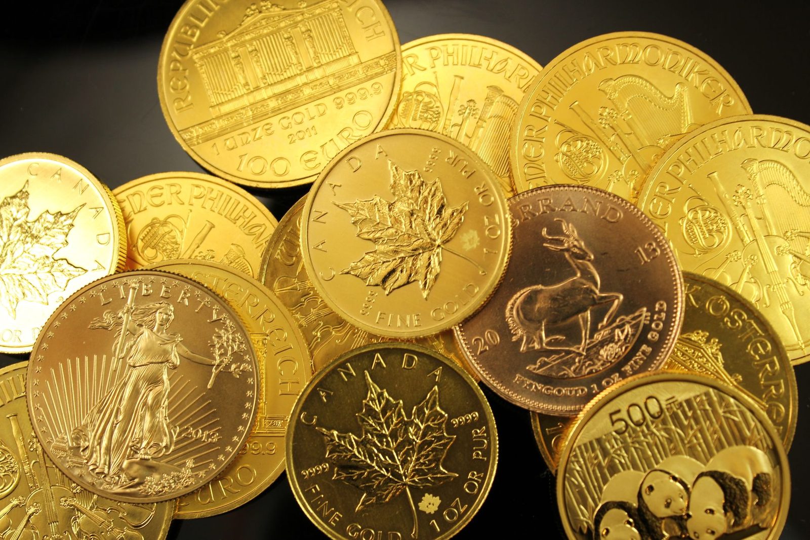 Monedas de oro de una onza amontonadas sobre una superficie oscura