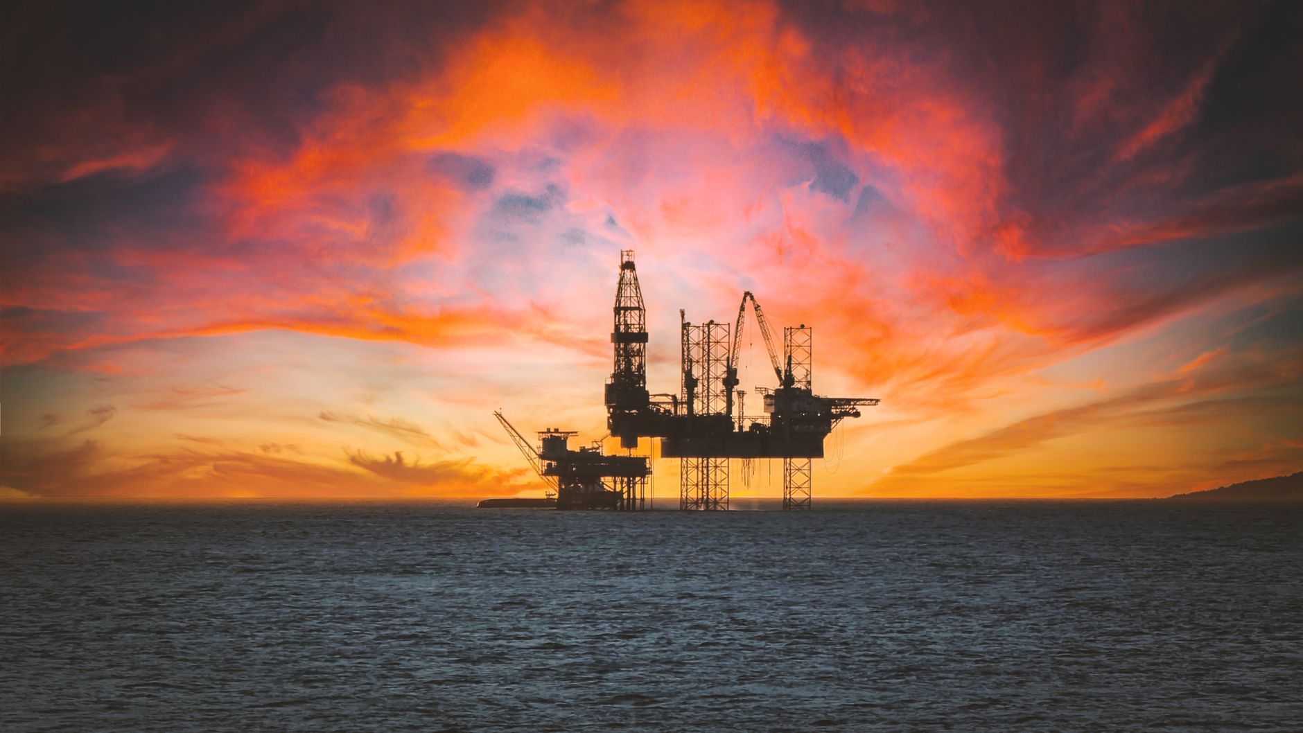 Plataforma petrolera en alta mar recortada contra el cielo al atardecer