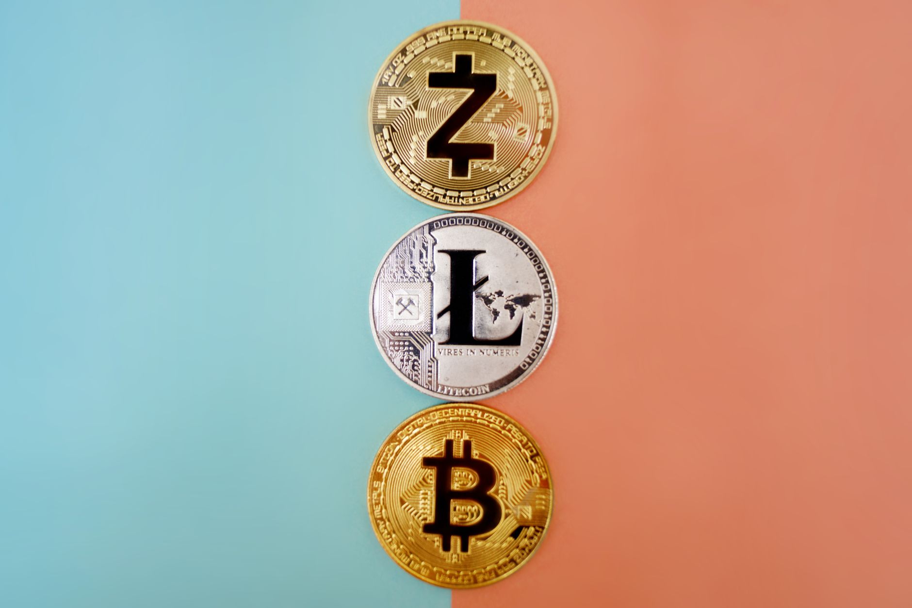 Monedas físicas de Zcash y Litecoin alineadas sobre una de Bitcoin en un fondo de dos colores