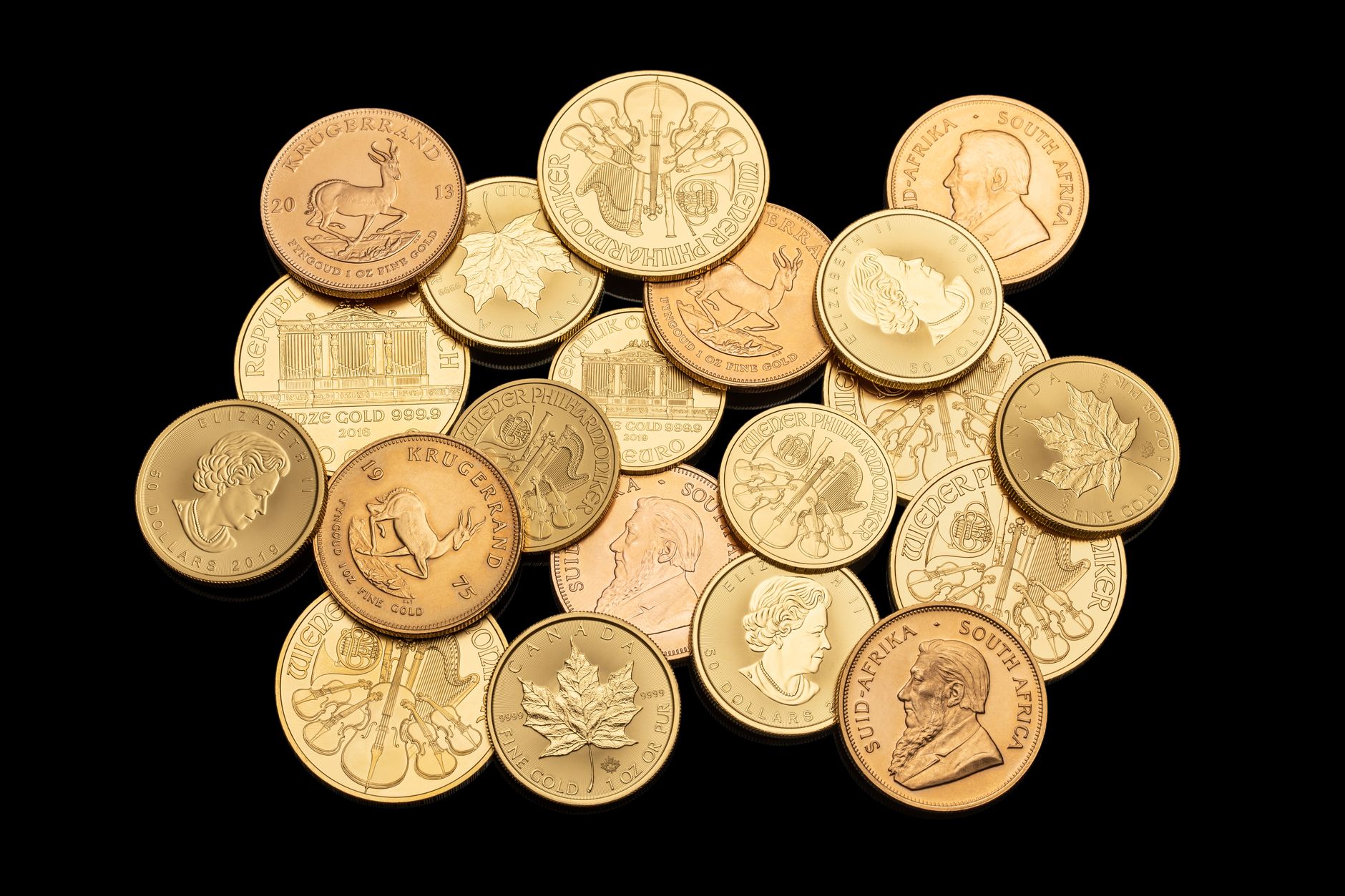 Monedas de oro de inversión de distintos países apiladas sobre un fondo negro