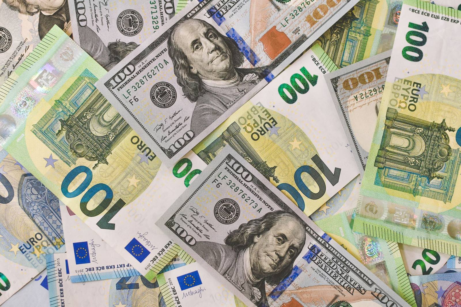 Billetes de cien dólares y de cien euros mezclados sobre una superficie