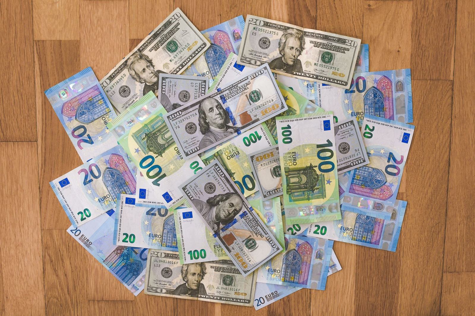 Billetes de cien dolares y de euros extendidos sobre un piso de madera