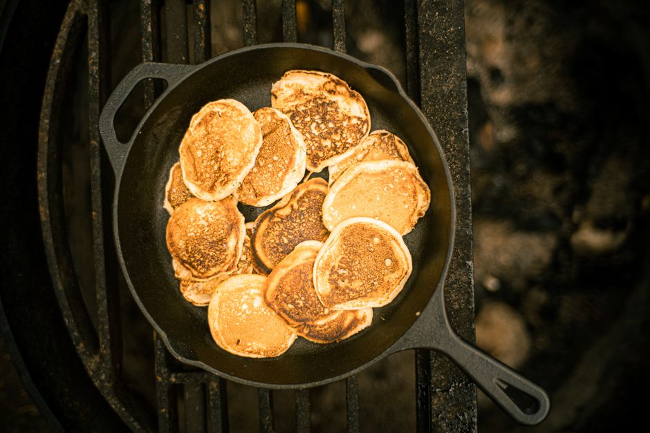 Tortitas doradas cocinándose en una sartén de hierro fundido sobre una parrilla, vistas desde arriba