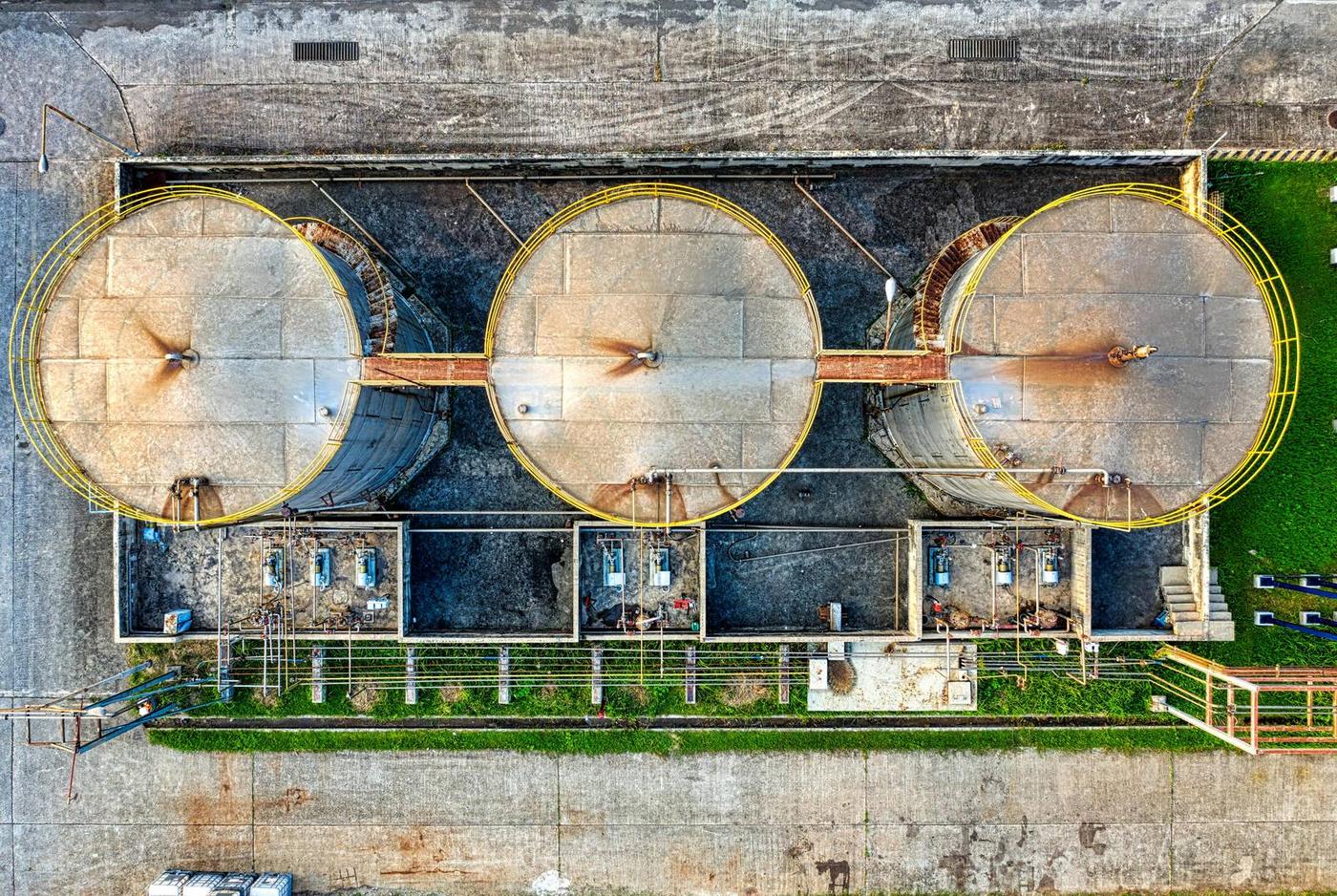 Vista aérea de tres grandes tanques industriales redondos de metal con pasarelas amarillas circundantes