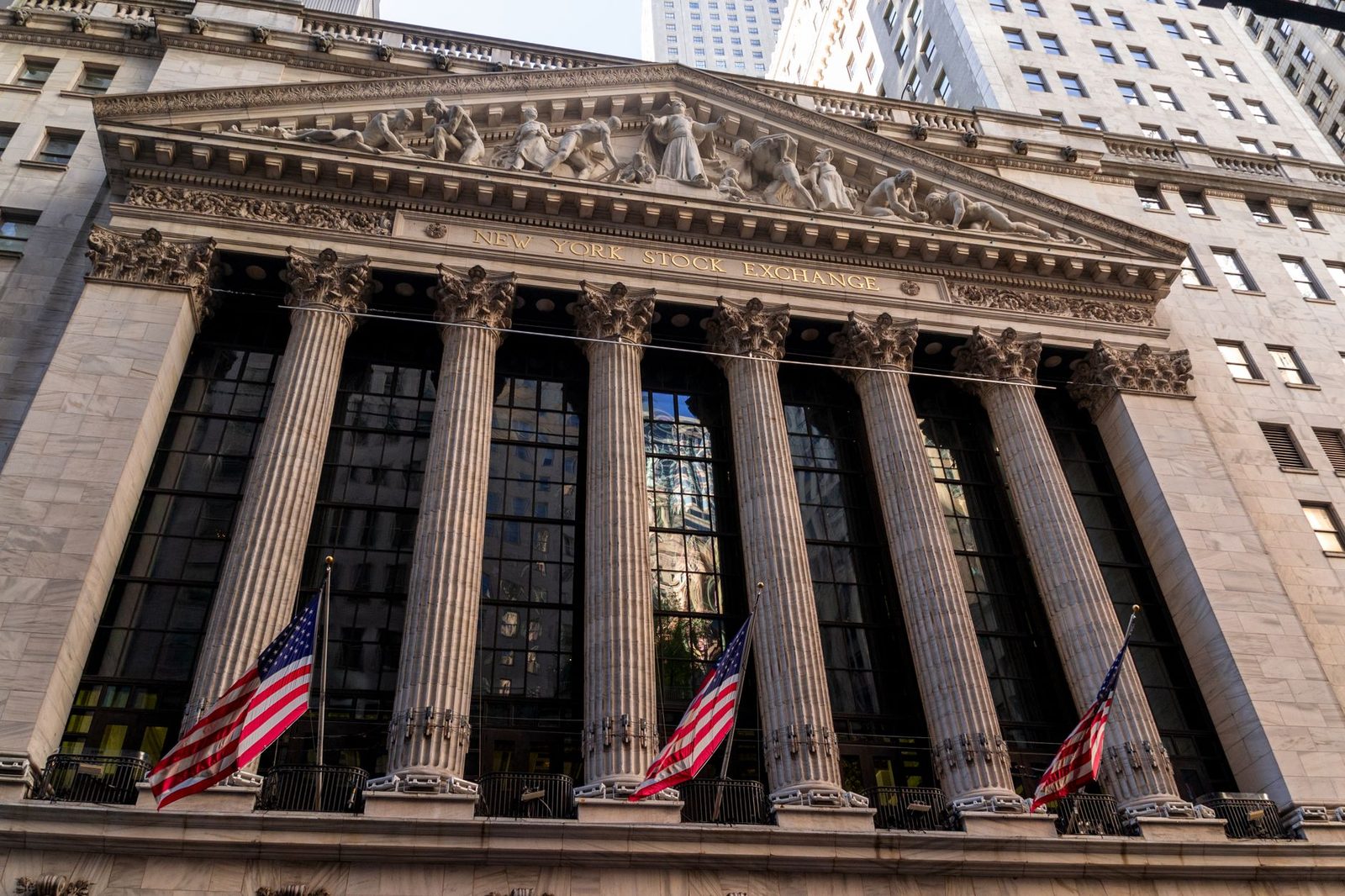 Fachada neoclásica de columnas de la Bolsa de Nueva York con tres banderas de Estados Unidos colgadas al frente