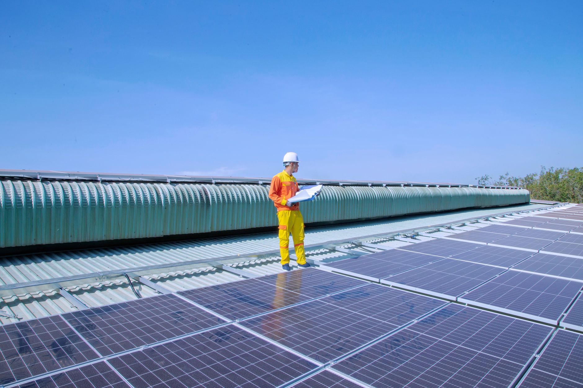 Un tecnico revisa sobre el tejado una instalacion de paneles solares con su carpeta de comprobaciones