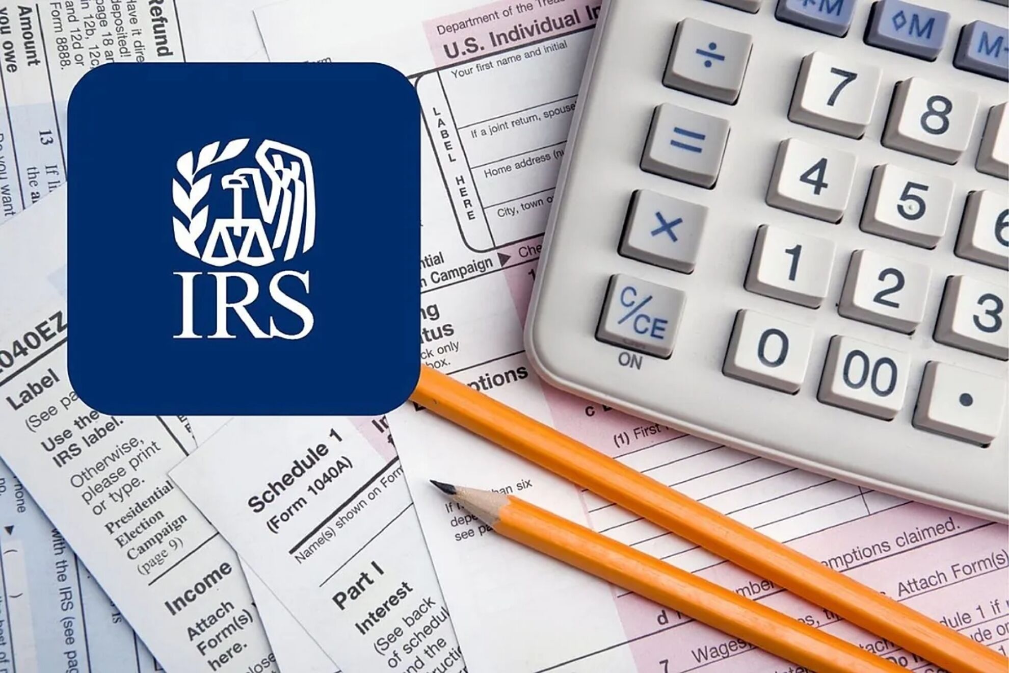 Formularios 1040 del IRS con una calculadora y dos lápices sobre la mesa