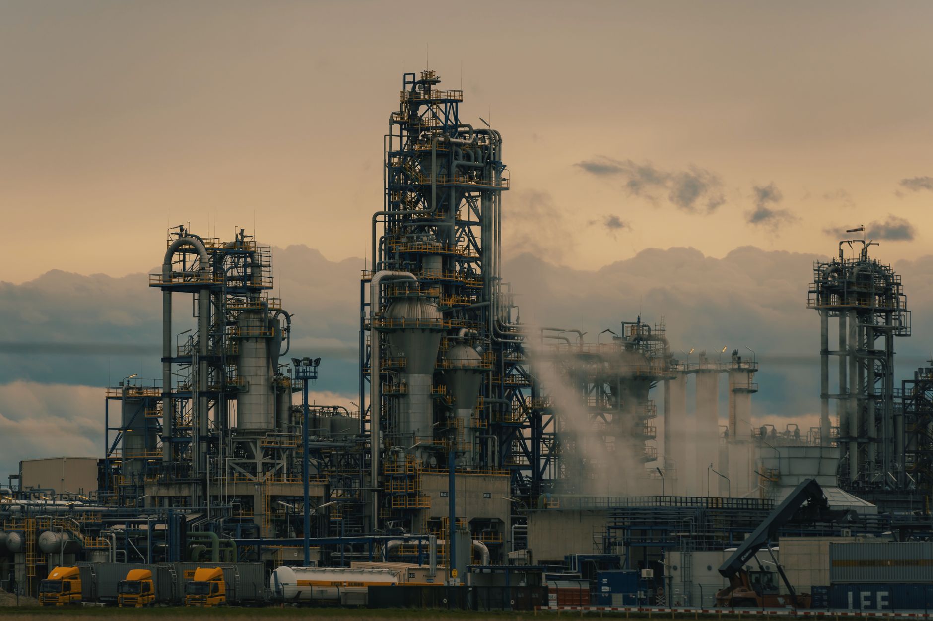 Torres y tuberías de una refinería de petróleo recortadas contra el cielo al anochecer