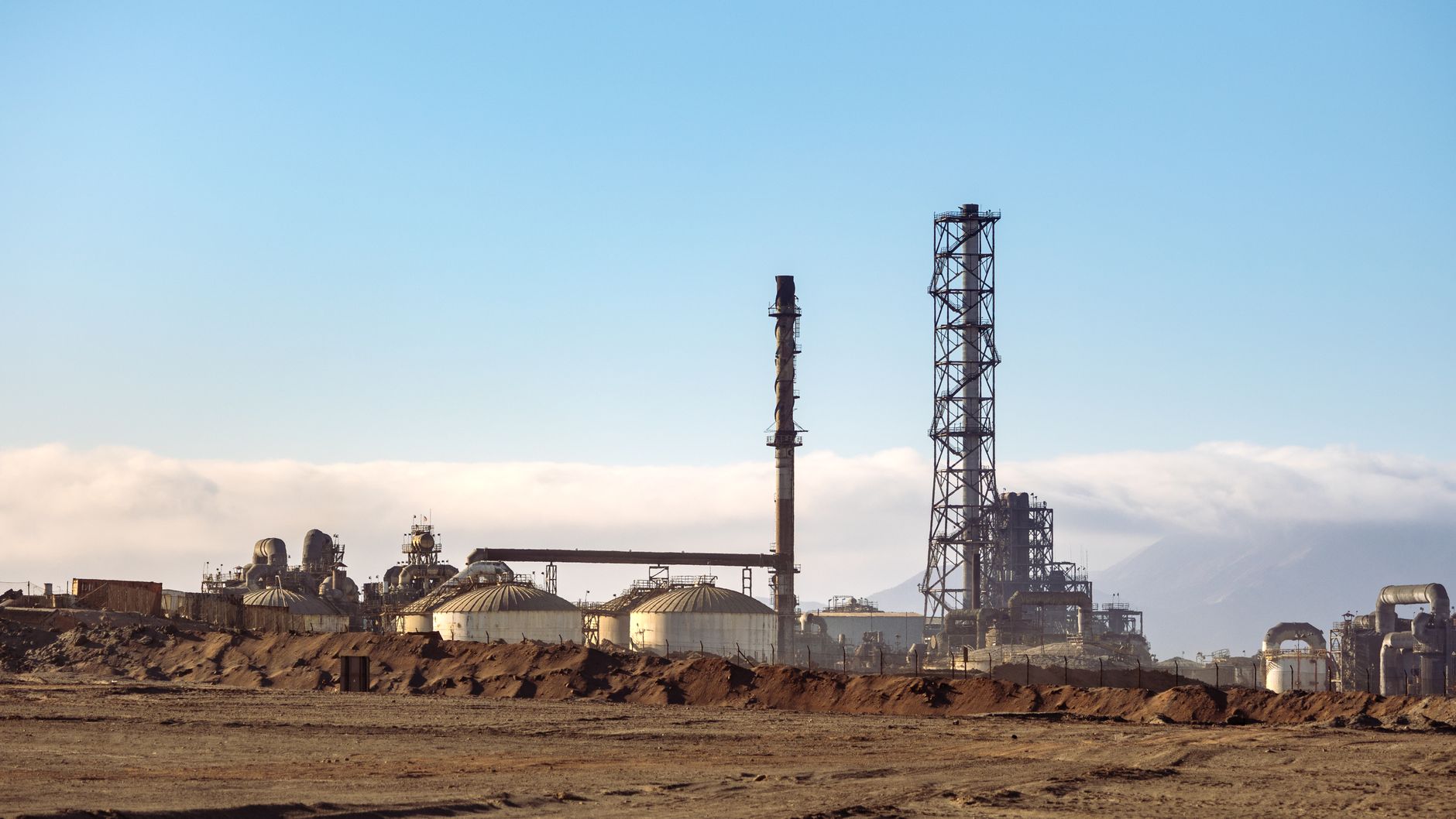 Refinería de petróleo con torres y tanques de almacenamiento en una zona árida