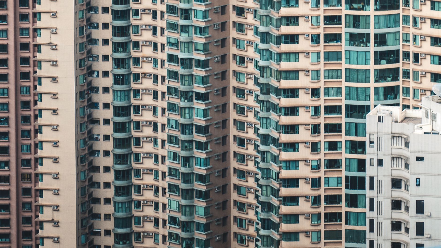Fachadas de varias torres de apartamentos muy juntas, con balcones, cortinas y equipos de aire acondicionado en cada piso