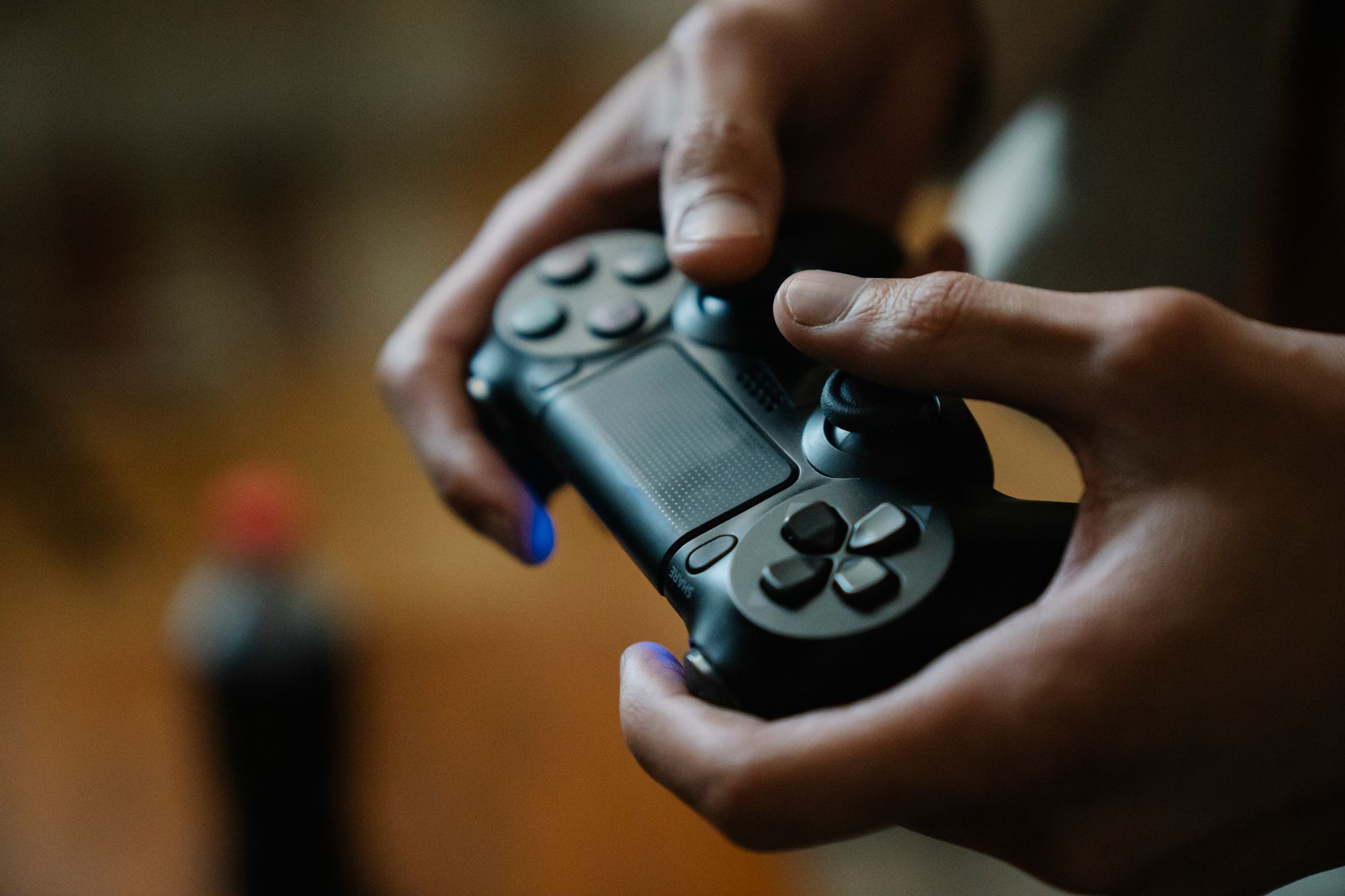 Manos de una persona pulsando los botones de un mando de consola mientras juega en casa