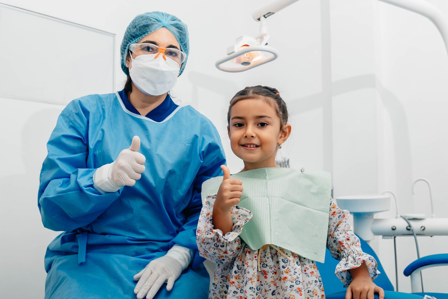 Una niña sonríe junto a su odontóloga al terminar la revisión dental en la clínica