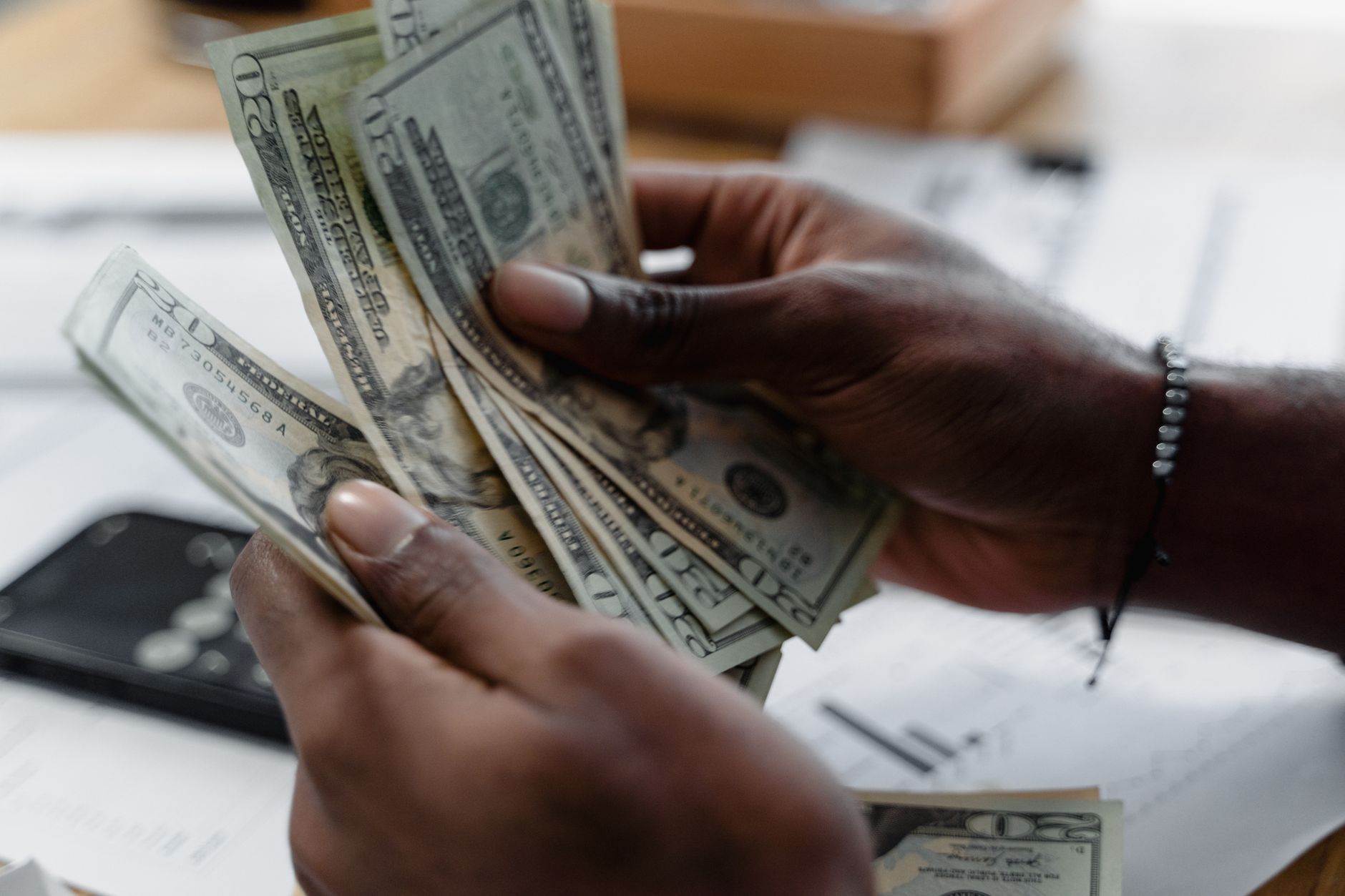 Manos contando billetes de dolar sobre el escritorio para juntar el enganche