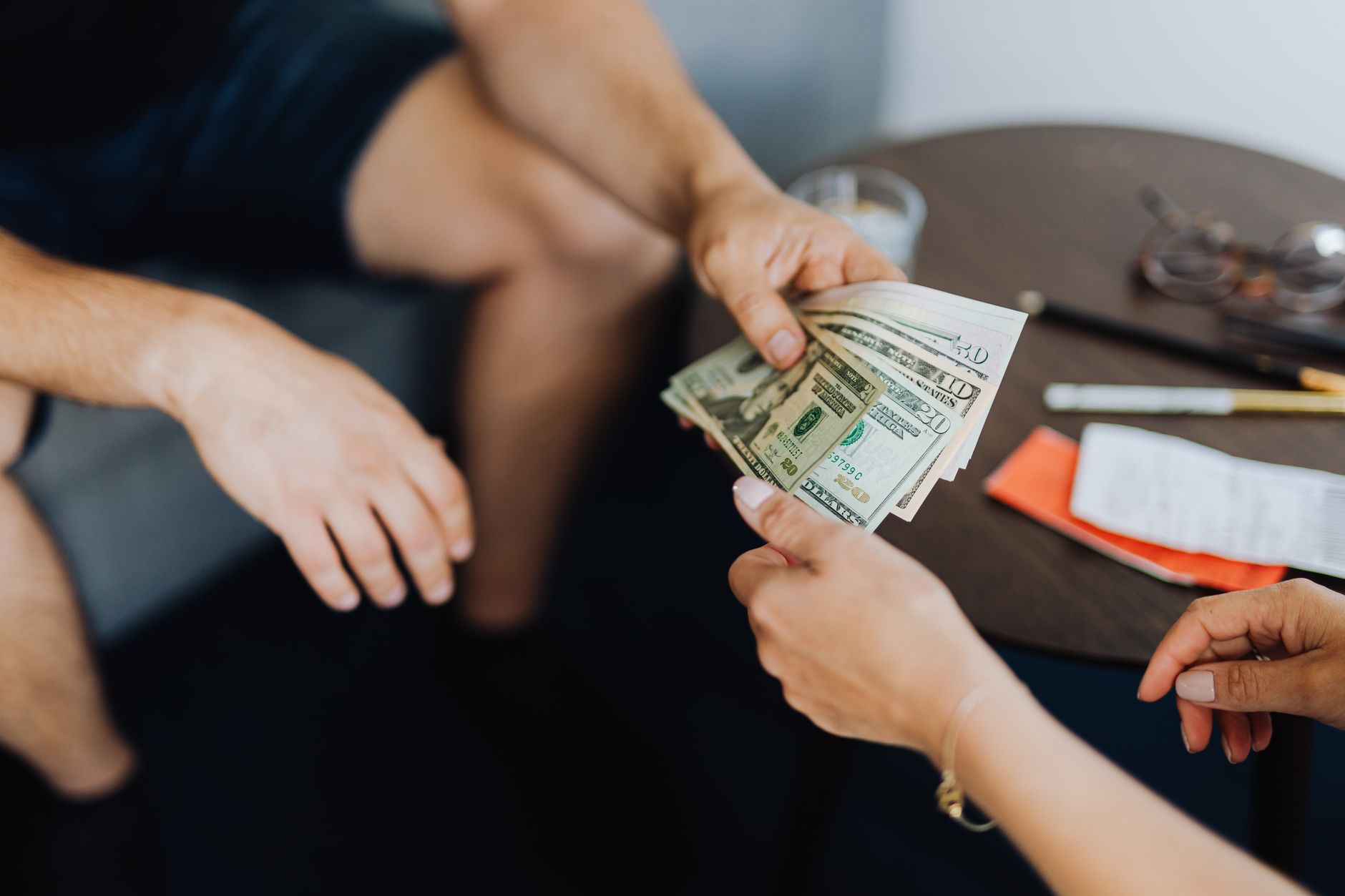 Dos manos se pasan varios billetes de diez y veinte dólares sobre una mesa