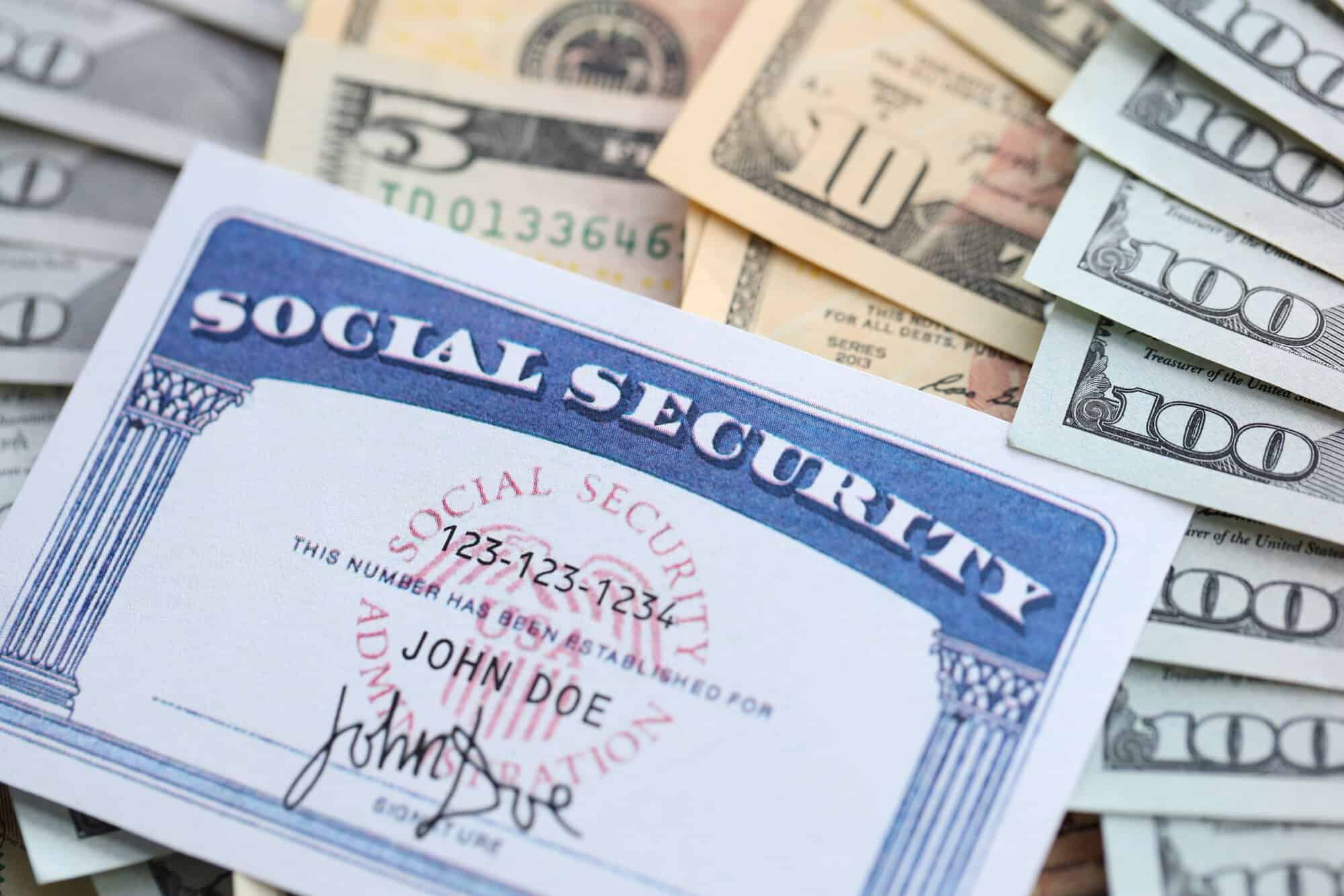 Una tarjeta de seguridad social a nombre de John Doe sobre varios billetes de dólares estadounidenses.