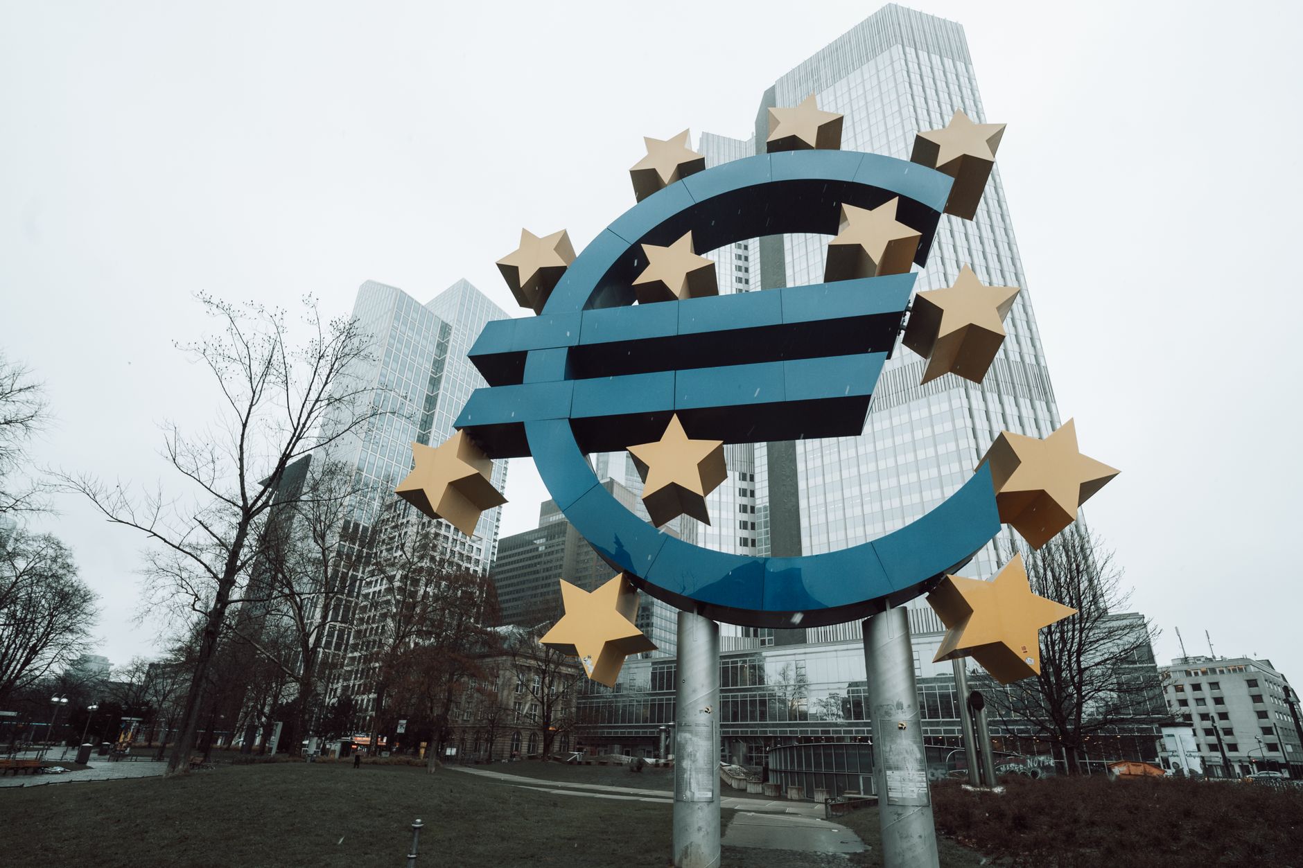 Escultura del símbolo del euro rodeada de estrellas frente a los rascacielos de Fráncfort