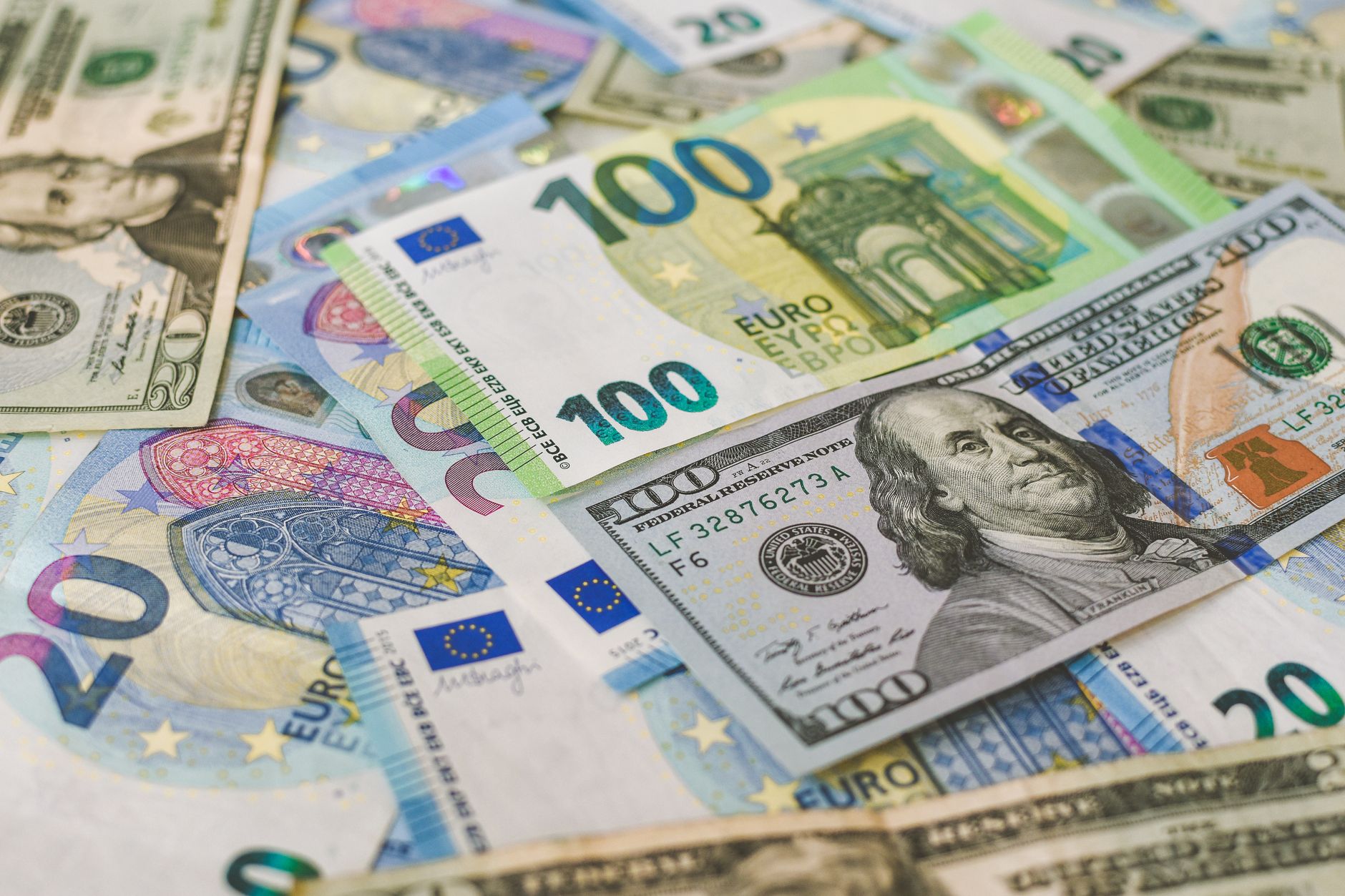 Billete de cien euros apoyado sobre uno de cien dólares, entre billetes de veinte de ambas monedas