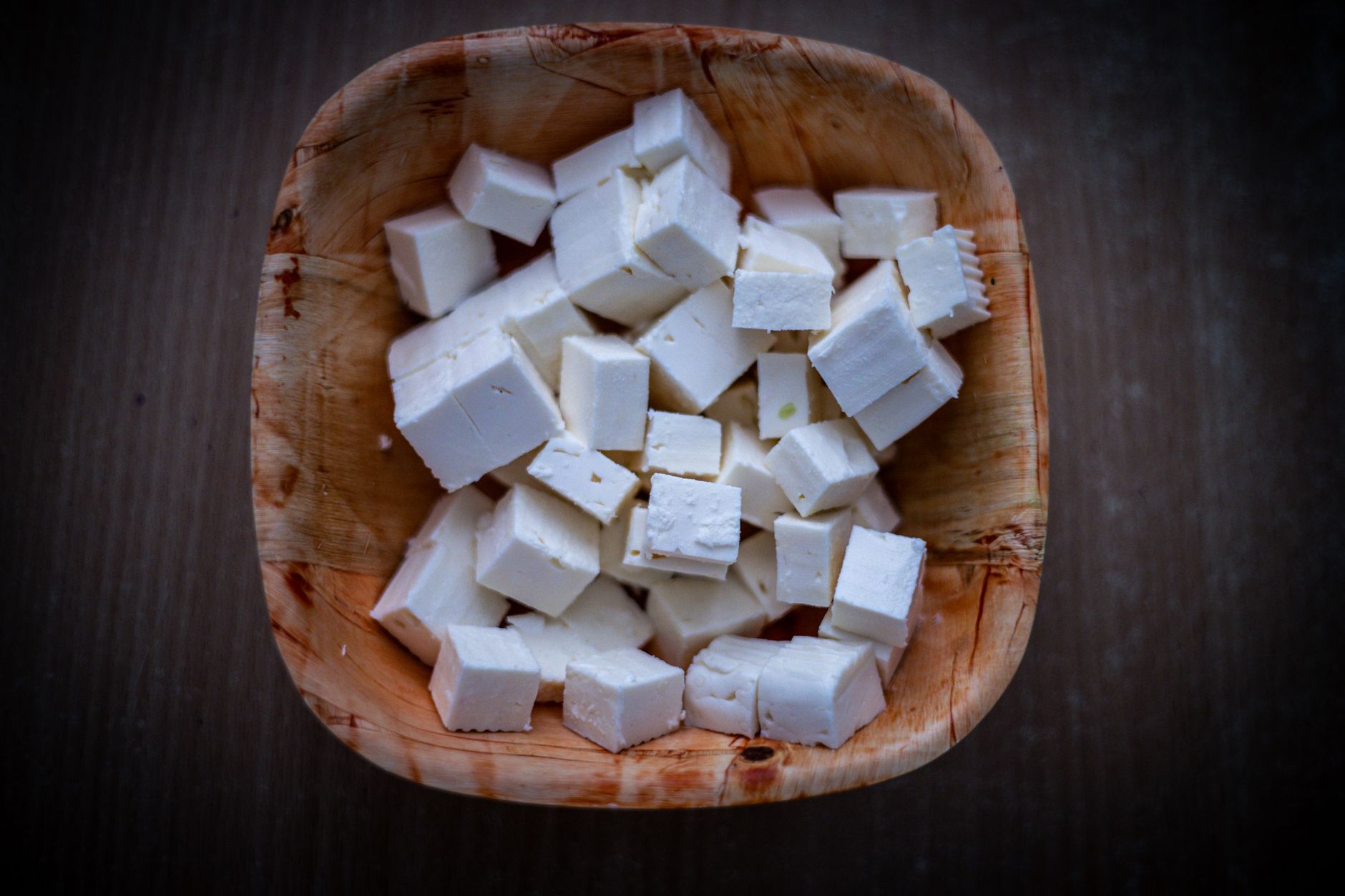 Cubos de queso blanco fresco, tipo feta, dentro de un bol de madera visto desde arriba