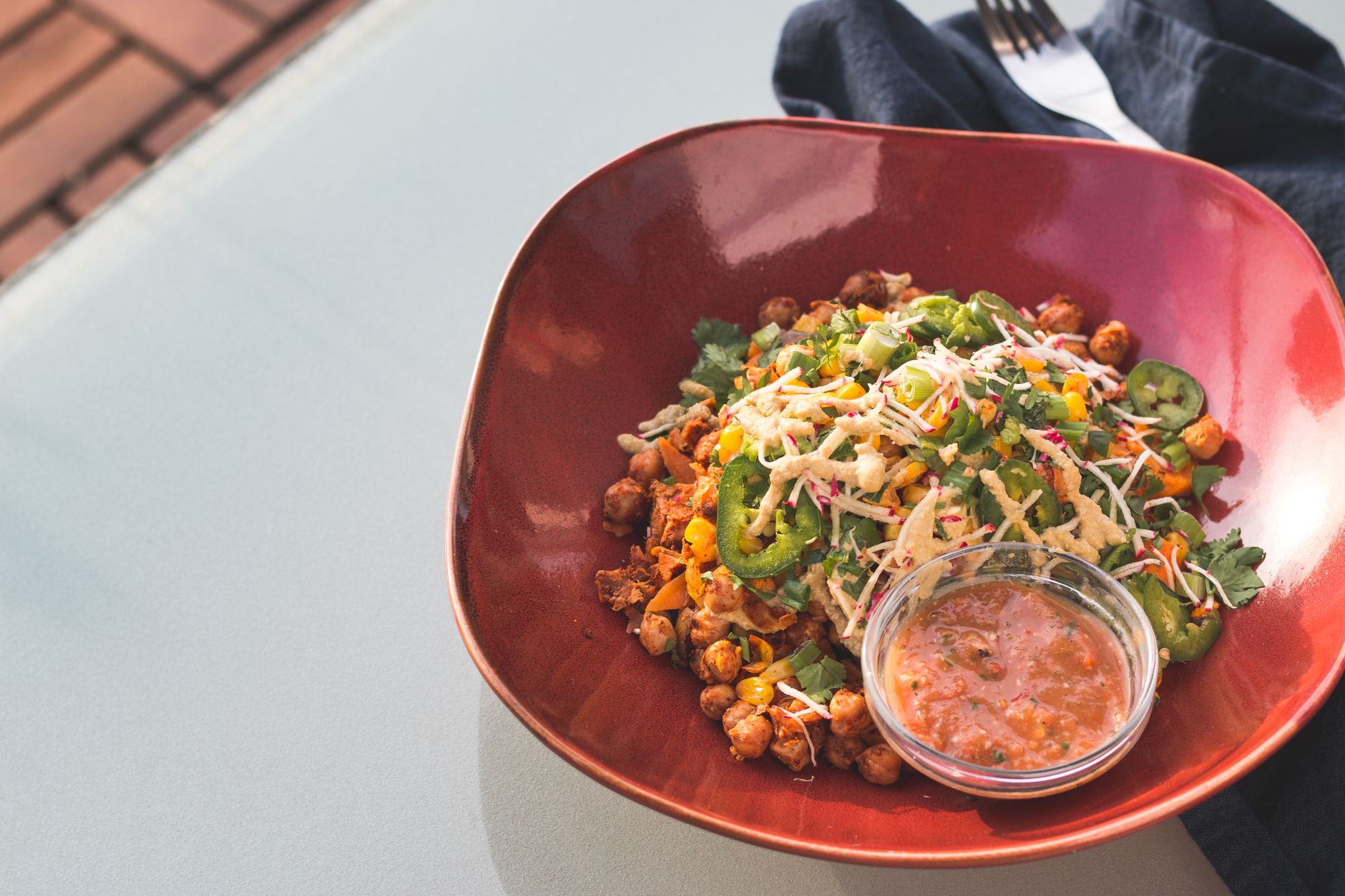 Bowl de garbanzos especiados con maíz, rábano y cilantro servido con salsa aparte