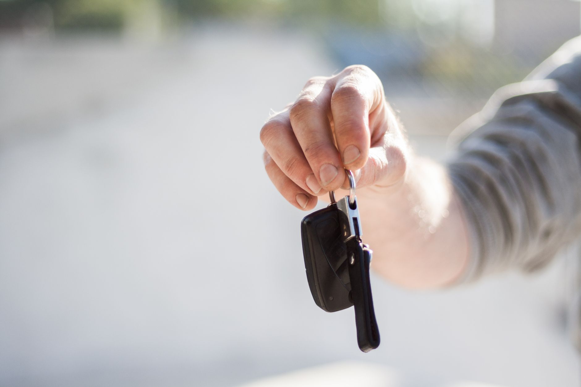 Una mano extiende las llaves de un carro para prestárselo a otra persona